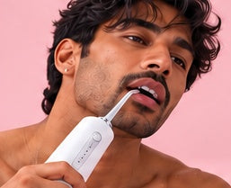 Pink Pulse water flosser lifestyle image without visible water spray, cropped without borders